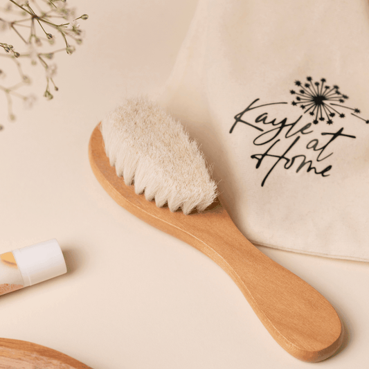Natural dry brush with wooden handle and firm bristles, placed on a white towel, symbolising holistic skincare and detox rituals.