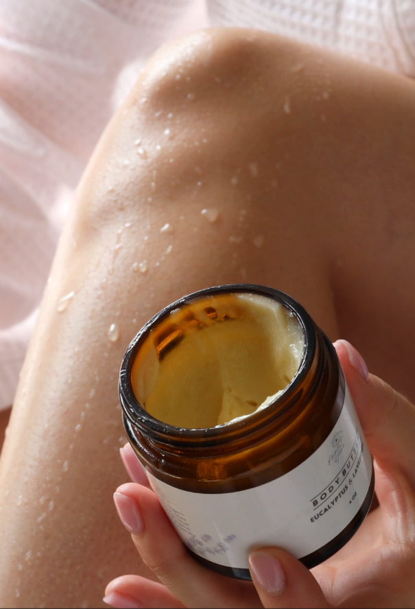 Person applying cream to their leg with a jar of cream in hand