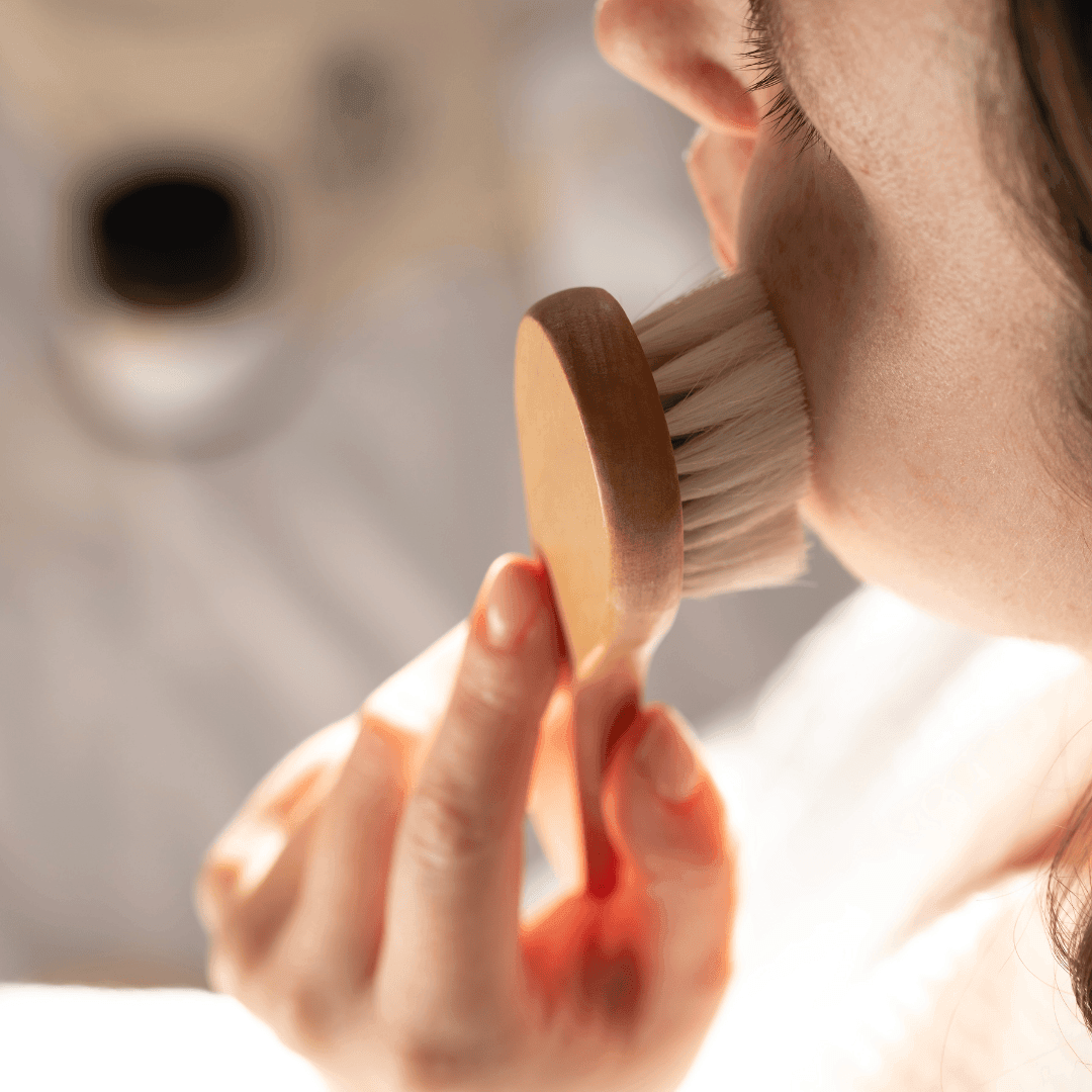 Lymphatic drainage facial massage using a dry brush to reduce puffiness.