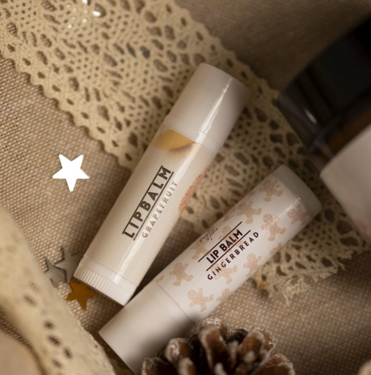 Natural lip balms displayed on lace fabric, with a pinecone accent, showcasing eco-friendly, handmade skincare products with organic ingredients.