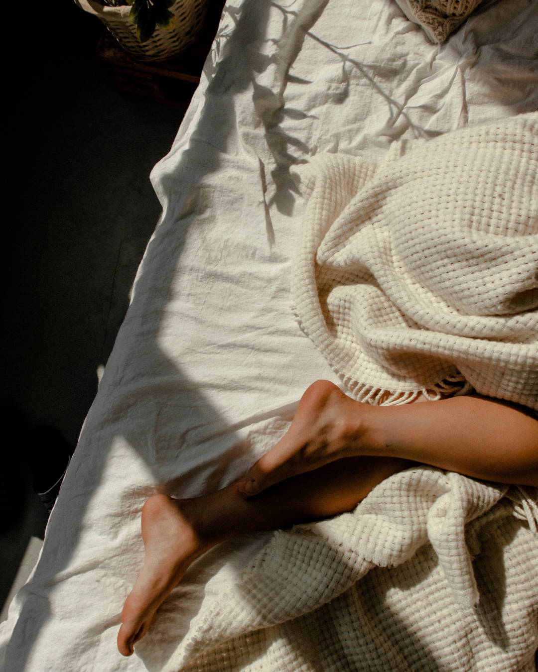 Relaxing feet tucked under a cozy quilt, symbolising restful sleep and comfort.