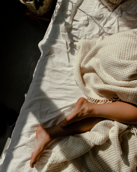Relaxing feet tucked under a cozy quilt, symbolising restful sleep and comfort.