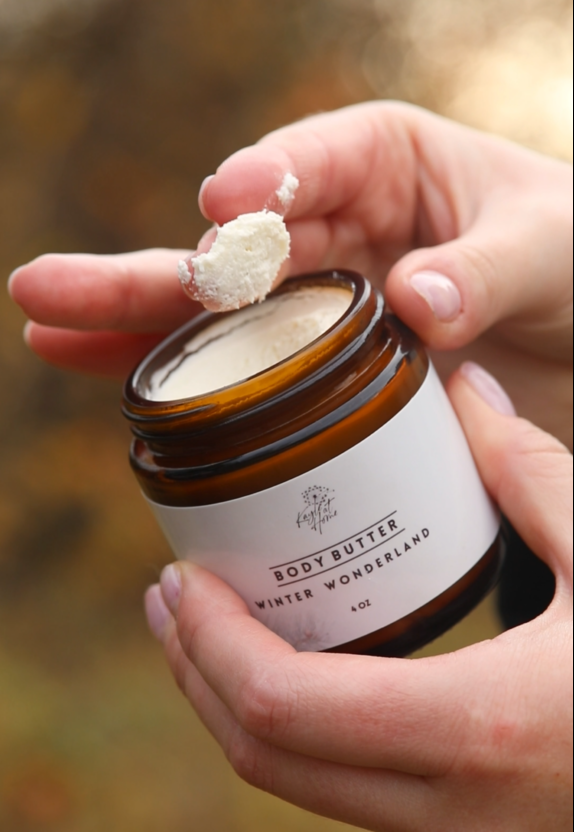 Open jar of holiday whipped body butter with a creamy, fluffy texture, held gently in hand to show its light, whipped consistency.